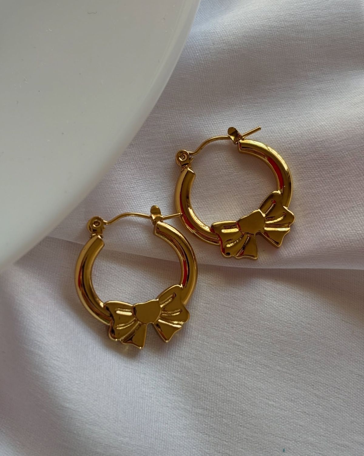 Gold color bow-shaped hoop earrings made of quality material with anti-tarnish finish, elegant jewelry for women.