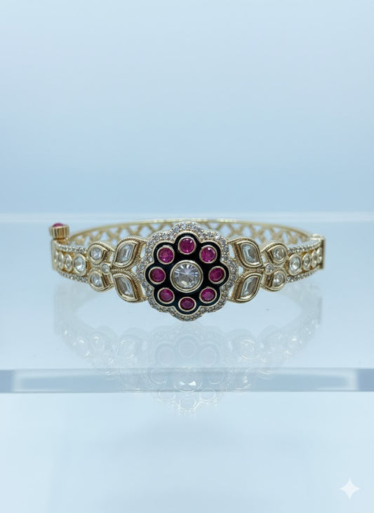 Golden bracelet with a decorative center featuring red stones