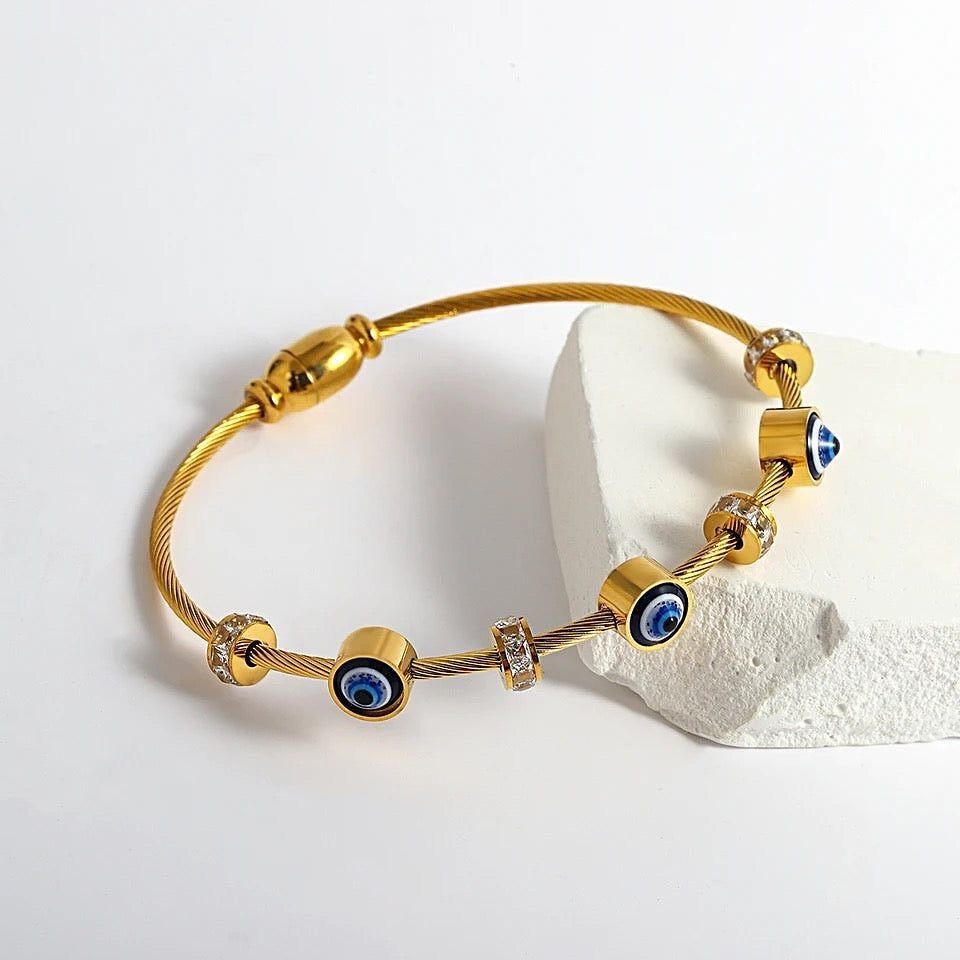 Gold bracelet with blue eye charms on a white background