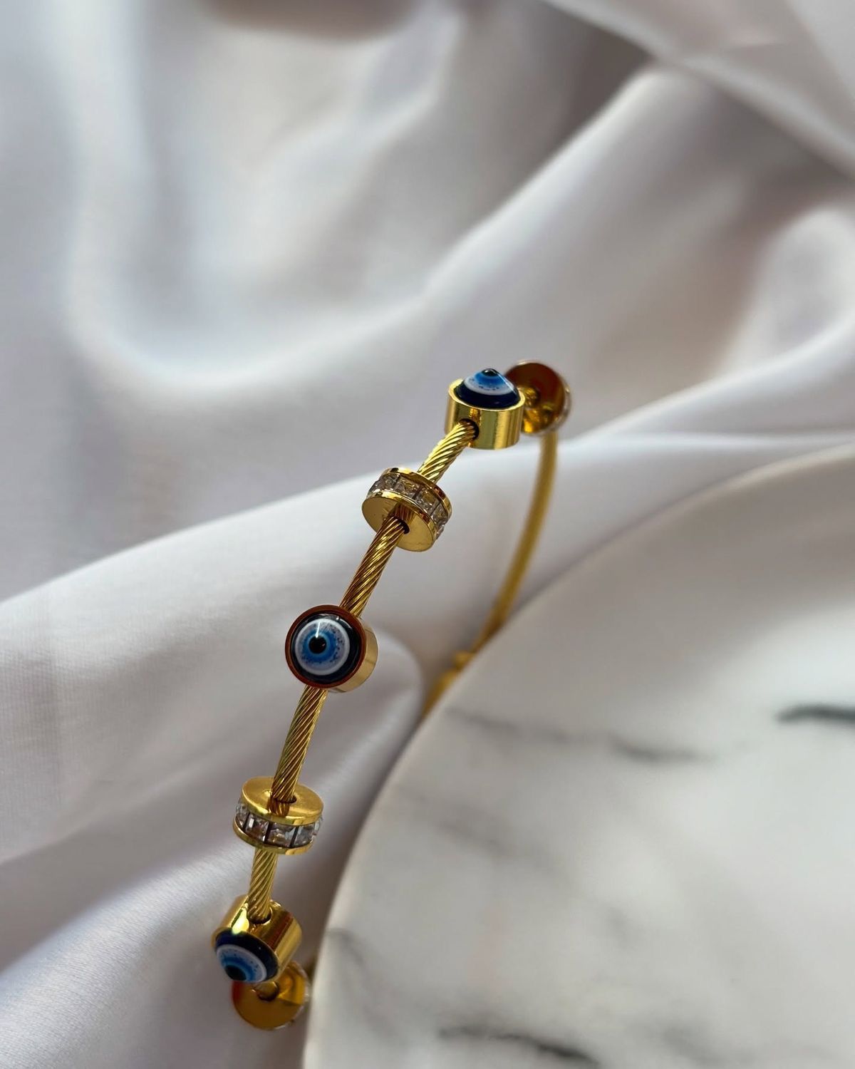 Gold bracelet with blue gemstones on a white fabric background