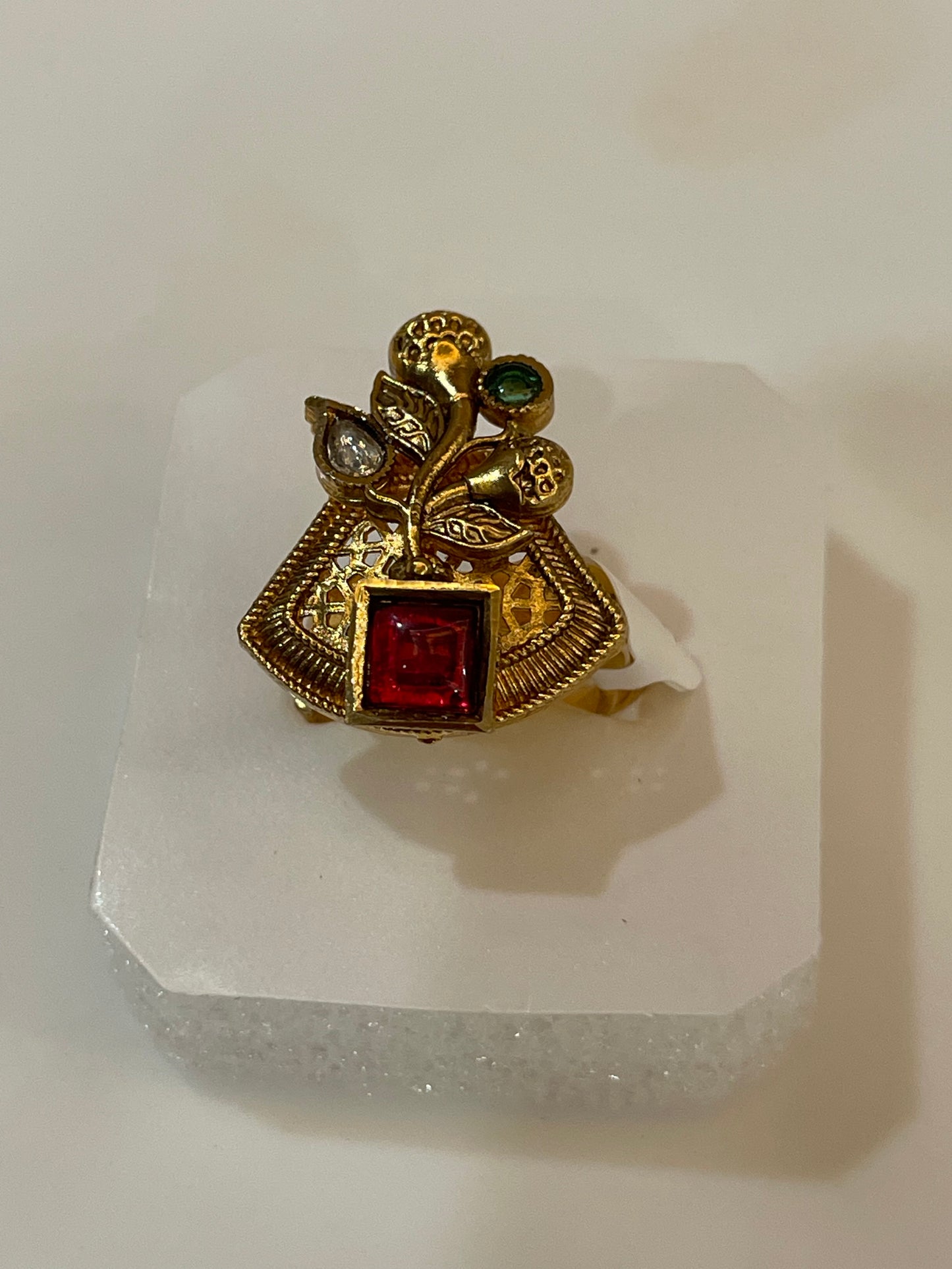 Golden plated ring petal shaped studded with red, white and green stones