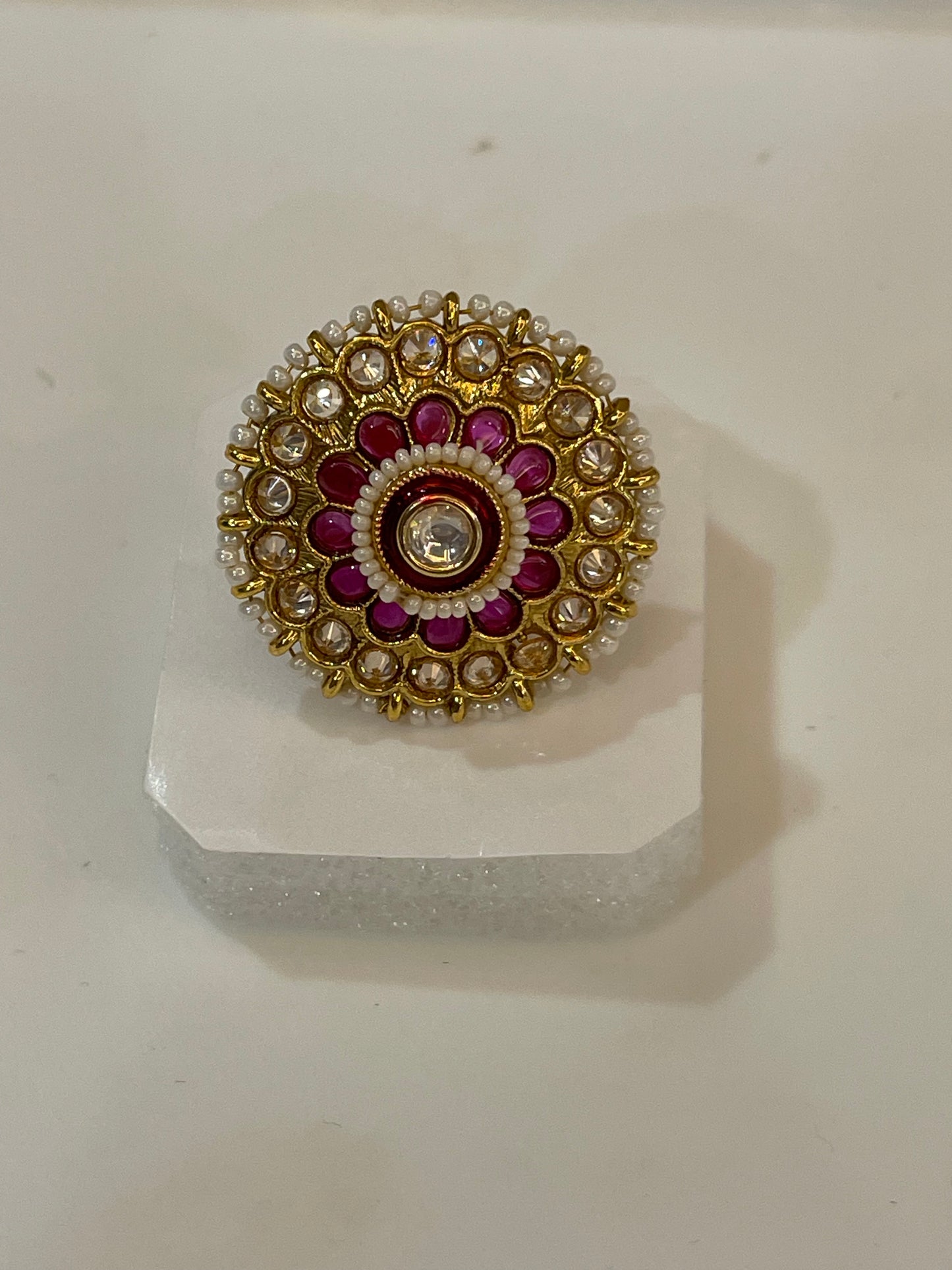 Golden Kundan ring with gold, red, and white stones design.