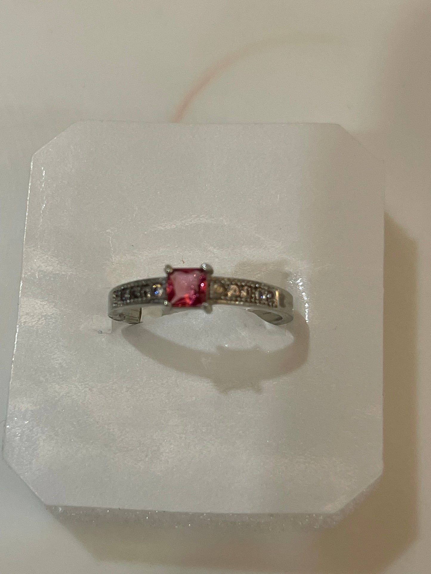 Silver plated ring with a red gemstone.