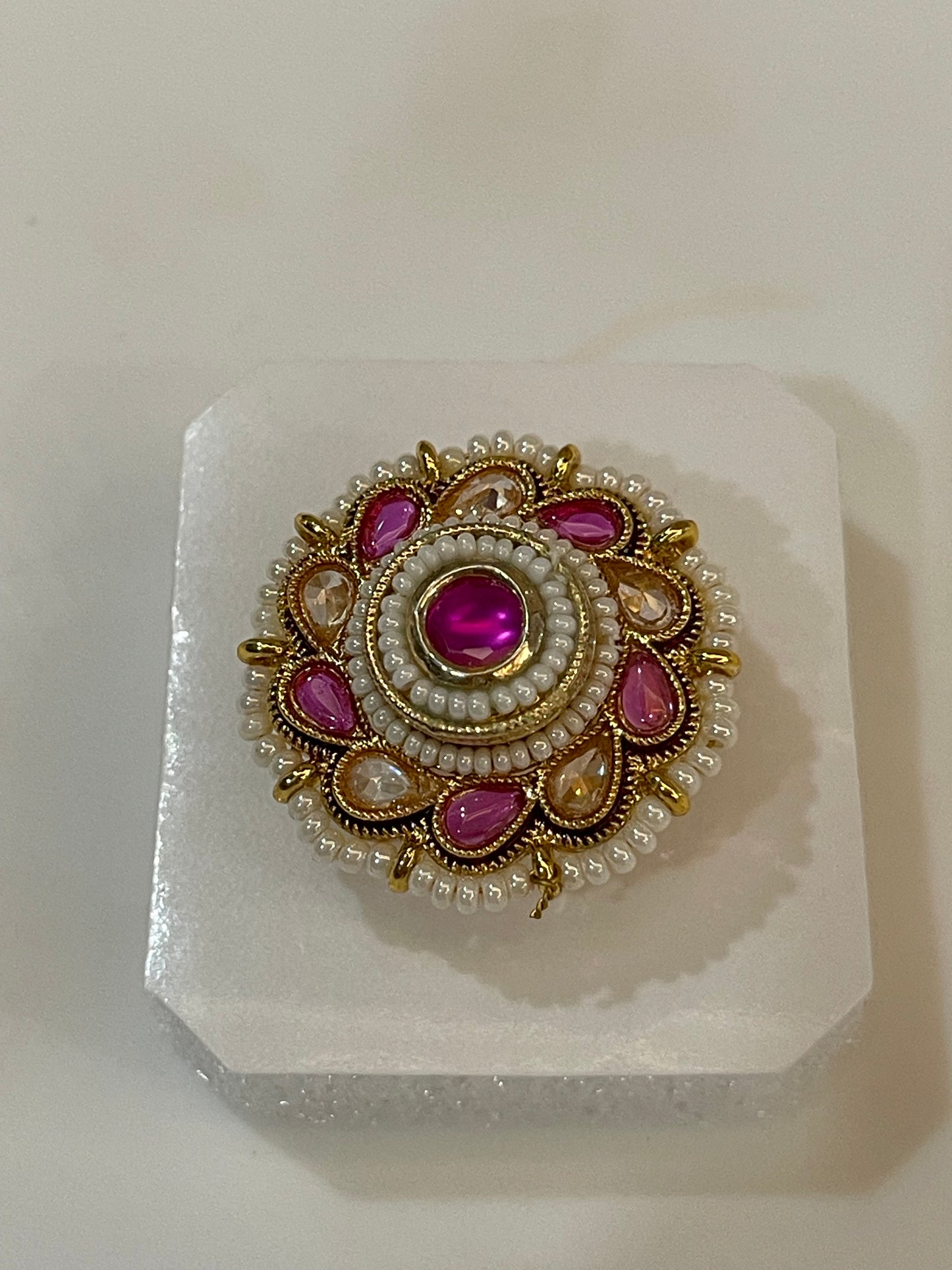 Polki ring with pink and yellow  gemstones surrounded by pearls and golden accents.