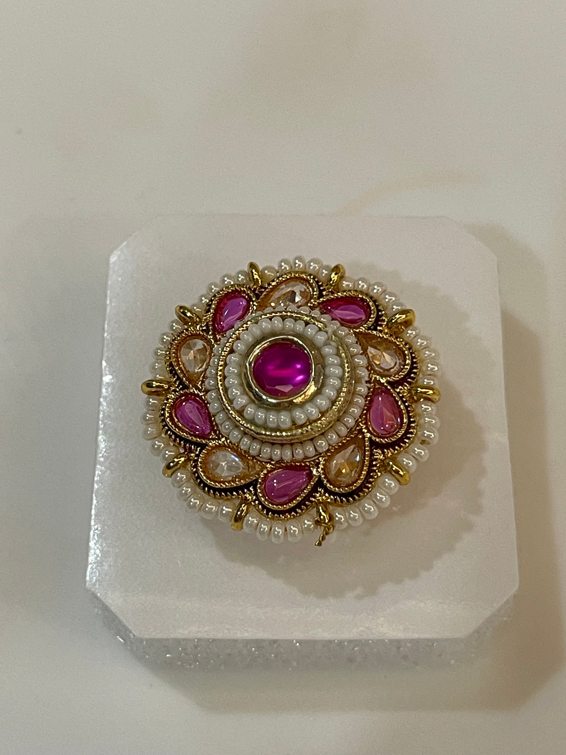 Polki ring with pink and yellow  gemstones surrounded by pearls and golden accents.